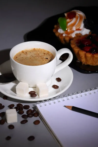 Cup of coffee, cakes and notebook on dark background — Stock Photo, Image