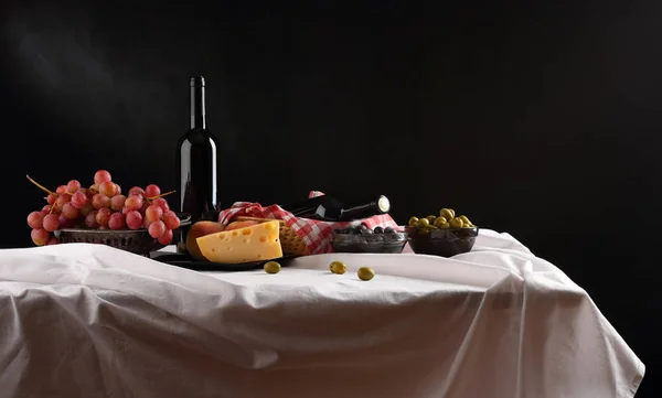 Panorama con vino, queso, uvas y aceitunas sobre un fondo oscuro — Foto de Stock