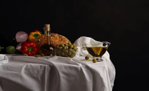 Кувшин оливкового масла, ваза с оливками и фруктами на темной спинке — стоковое фото