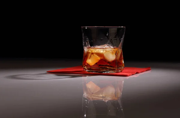 光沢のあるテーブルの上に氷のあるウイスキーのガラスと暗い背景 — ストック写真