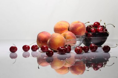 Şeftali ve kiraz beyaz bir masa üzerinde ve hafif bir arka plan