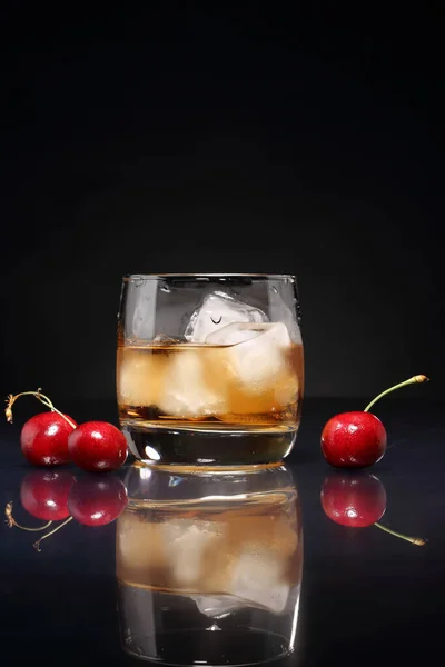 Ein Glas Whisky Mit Eis Und Kirschbeeren Auf Einem Glänzenden — Stockfoto