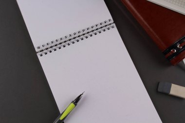 Gri arkaplanda çizim defteri, mekanik kalem ve silgi.