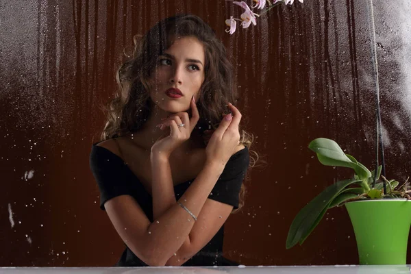雨滴と窓の外の黒いドレスの美しい少女の肖像画 — ストック写真