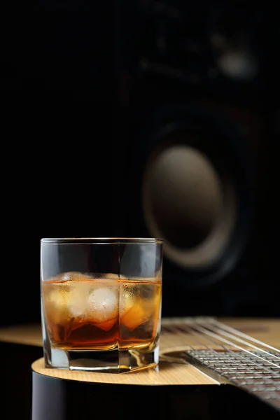 ギターと音の柱の後ろに氷のあるウイスキーのガラス — ストック写真