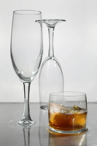 2つの空のシャンパングラスと軽い背景のウイスキーのガラス — ストック写真
