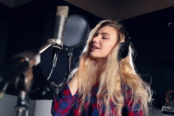 Müzik seni ifade eder! Yan görünüm portre kulaklık mikrofon önünde bir şarkı kayıt ile genç bir kadın şarkıcı.