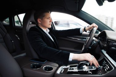 Acele değil! Sürücü koltuğuna oturan ve dikkatle otomobil sürüş yakışıklı zeki ciddi girişimci.