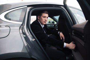 Zeki ve akıllı olun! Rahat yeni arabasına oturan ve ofise gidecek bir yakışıklı ciddi genç işadamı.