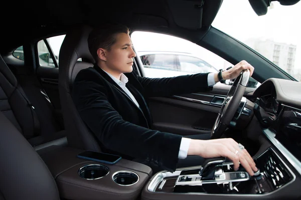 Δεν βιάσου! Όμορφος smart σοβαρό επιχειρηματία κάθεται στο κάθισμα του οδηγού και προσεκτικά οδήγηση αυτοκινήτου. — Φωτογραφία Αρχείου