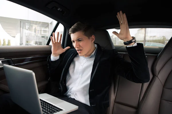 ¡Anda y no te rindas! Atractivo joven inteligente que va al trabajo en la oficina en coche y tiene problemas, mientras usa su computadora . — Foto de Stock