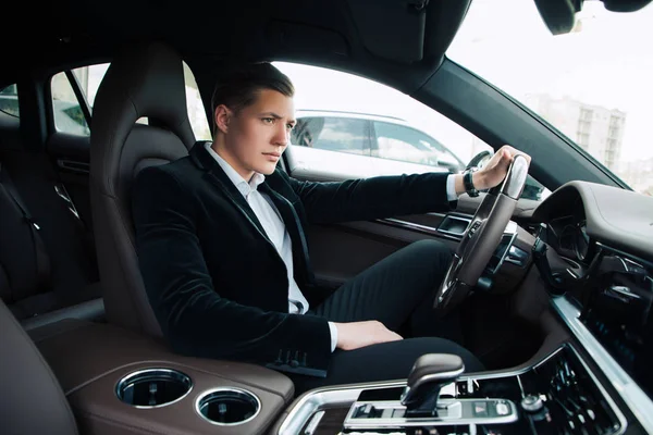 stock image Deep gaze! Serious successful young handsome businessman going to the work in the office by car, while sitting behind the wheel. 