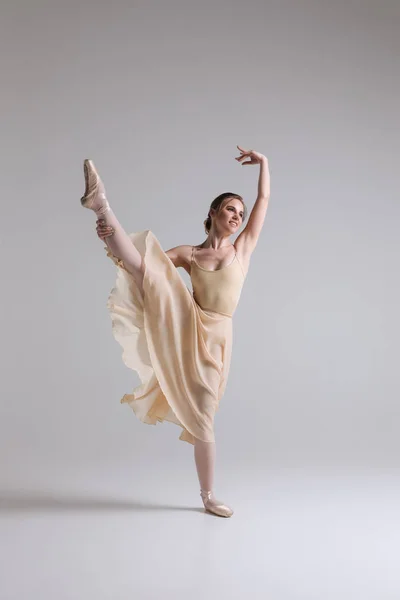 Haciendo un baile! Elegante atractiva encantadora bailarina joven en traje beige posando en los dedos de los pies en el fondo del estudio . —  Fotos de Stock
