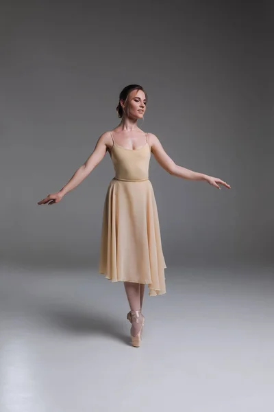 ¡Un poco de ternura! Retrato completo de la joven bailarina de ballet moderna sonriente ejercitándose sobre el fondo gris aislado del estudio . —  Fotos de Stock