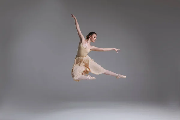 ¡Muéstrate! Hermosa bailarina guapa que muestra poses clásicas de ballet y salta al aire sobre el fondo gris . —  Fotos de Stock