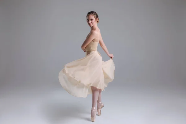 Life flows through dance! Full length portrait of the young attractive gorgeous ballerina dancing on the isolated background indoors.