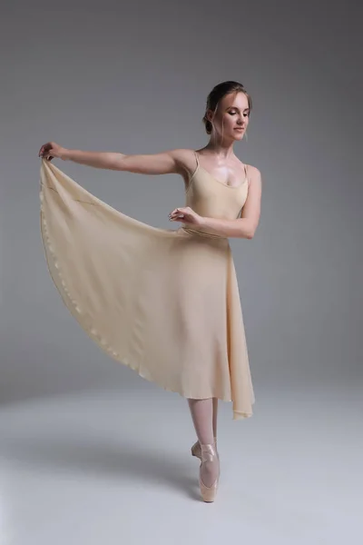 ¡Los placeres sublimes de la danza! Bastante guapo encantadora bailarina de ballet profesional en el vestido beige haciendo una pose en un estudio . —  Fotos de Stock
