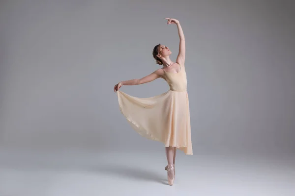 Вечная интерпретация жизни! Полная фотография молодой красивой балерины, выполняющей движения на светлом фоне . — стоковое фото