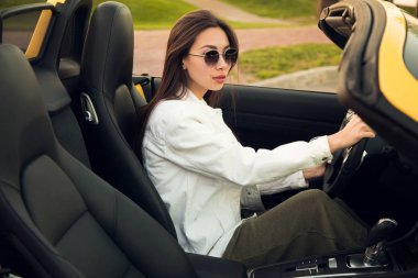 Emin olun! Çekici yakışıklı zeki ciddi genç güneş gözlüğü ona sarı cabriolet direksiyonuna kadındır.