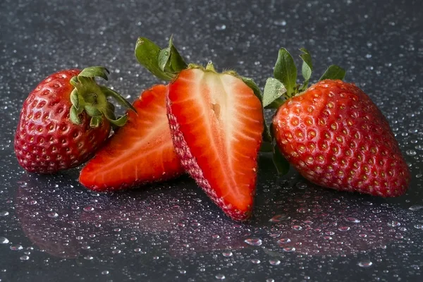 Red fresh strawberries on a black background with drops of water