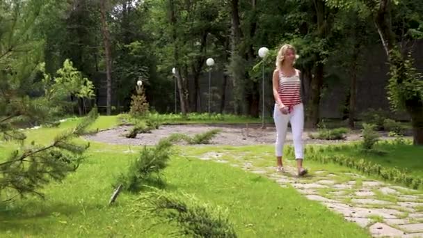 En vacker sexig blond flicka går i en Park i en fjäll skog på semester i ett spa-hotell i Ryssland. Lycklig blondin leende. — Stockvideo