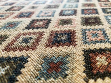 Döşeme kumaşı ya da halının yakın çekimi hassas bir şekilde dokunmuş karmaşık bir geometrik desen sergiliyor..