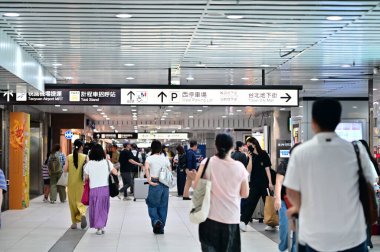 Tayvan - 21 Temmuz 2025: Taipei Ana İstasyonu 'ndaki yaya koridoru, Taoyuan Havalimanı MRT, taksi durağı ve yeraltı alışveriş caddelerinin yön işaretlerini gösteren yolcuları gösteriyor.