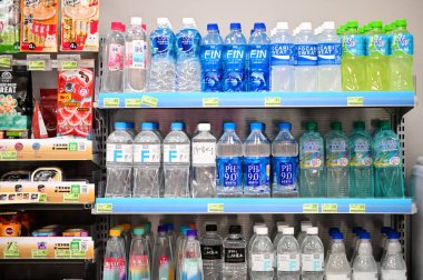 Taipei, Tayvan - Nisan. 04, 2025: Süpermarket ortamında su, renkli kapaklı spor içecekleri ve sıvılar da dahil olmak üzere çeşitli şişe içeceklerini gösteren üç kademeli perakende satış rafları.