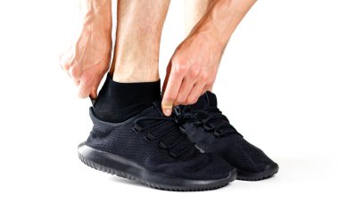 Bir adam bir kaşık ile siyah spor ayakkabı giyiyor. Spor için. Beyaz arka plan üzerinde izole.