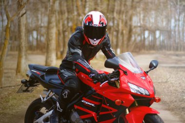 KRASNOYARSK, RUSSIA - April 21, 2018: Beautiful motorcyclist in full gear and helmet on a red and black Honda 2005 CBR 600 RR (PC37) clipart