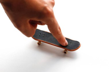 Klavye. Küçük bir kaykay ve bir el. Yakın çekim. Beyaz arka plan üzerinde izole