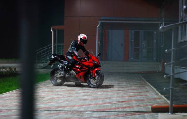 Krasnoyarsk, Rusya - 8 Eylül 2018: Güzel motosikletçi tam Dişli ve bir kırmızı ve siyah Honda 2005 Cbr 600 Rr (Pc37 karanlık gecede kask).