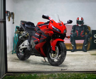 Krasnoyarsk, Rusya Federasyonu - 16 Ağustos 2018: Motosikletçi Dişli ve kask garajda oturur ve motosiklet görünüyor