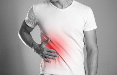 Adam onun tarafını tutuyor. Karaciğer ağrısı. Siroz. Ocak kırmızıyla vurgulanır. Yakın çekim. İzole arka plan.