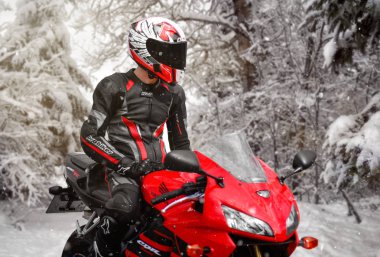 Krasnoyarsk, Rusya - 17 Temmuz 2018: Güzel motosikletçi tam Dişli ve kask bir kırmızı ve siyah Honda 2005 Cbr 600 Rr (Pc37). Kışın. Kar düşüyor