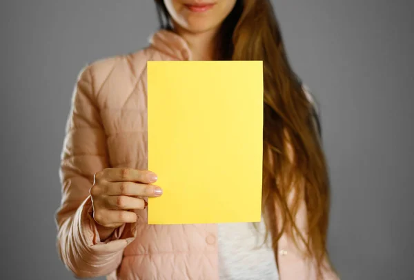 Bir Sıcak Kış Ceket Sarı Bir Broşür Tutan Bir Kadın — Stok fotoğraf