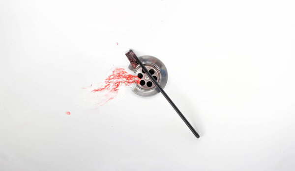 Toothpaste with blood in a ceramic sink. Bleeding gums. Close up.