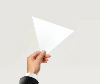 Beyaz gömlek ve siyah ceket bir beyaz üçgen parça kağıt tutan erkek elinde. Gri arka plan üzerinde izole. Portre.