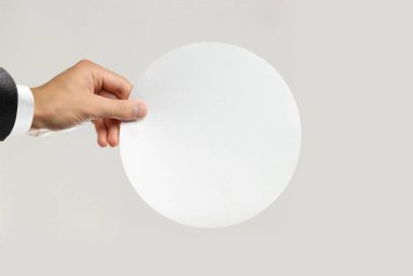 Beyaz gömlek ve siyah ceket beyaz bir levha tutan erkek elinde kağıt yuvarlak. Gri arka plan üzerinde izole. Portre.