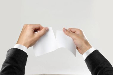 Beyaz gömlek ve siyah ceket RIP beyaz kağıdın erkek elinde. Gri arka plan üzerinde izole. Portre.