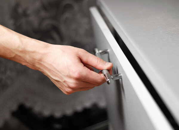 Рука открывает шкаф на кухне. Рука закрывает дверь на кухонном столе. Закрыть
.