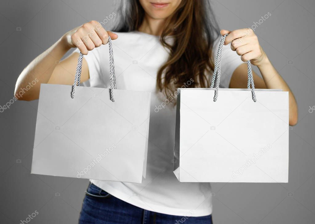 Girl holding a gray paper gift bag. Close up. Isolated background.