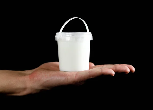 Hand holding a small white bucket. Close up. Isolated on white background.