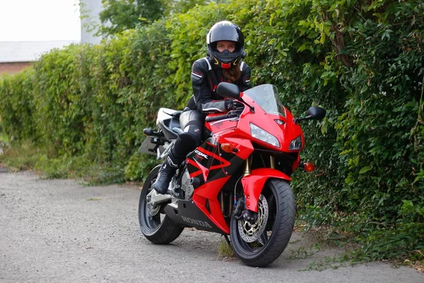 KRASNOYARSK, RUSSLAND - 23. Juni 2018: Schöne Motorradfahrerin in voller Ausrüstung und Helm auf einer rot-schwarzen Honda 2005 CBR 600 RR (PC37). — Stockfoto