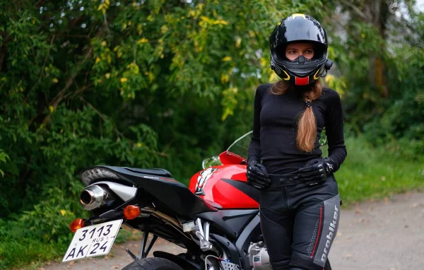 KRASNOYARSK, RUSIA - 23 de junio de 2018: Hermosa chica motociclista en marcha completa y casco en un Honda 2005 CBR 600 RR rojo y negro (PC37). — Foto de Stock