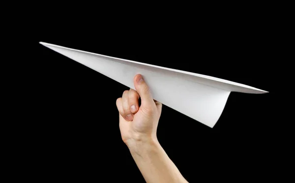Χέρι κρατώντας ένα λευκό χαρτί αεροπλάνο. Κοντινό. Απομονωμένος σε μαύρο — Φωτογραφία Αρχείου