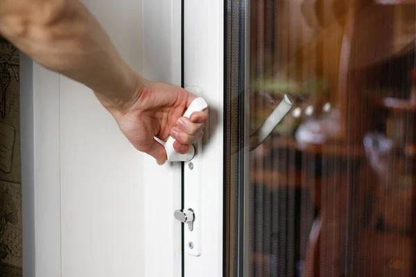 La main d'un homme ouvre une porte en plastique blanc. Gros plan — Photo
