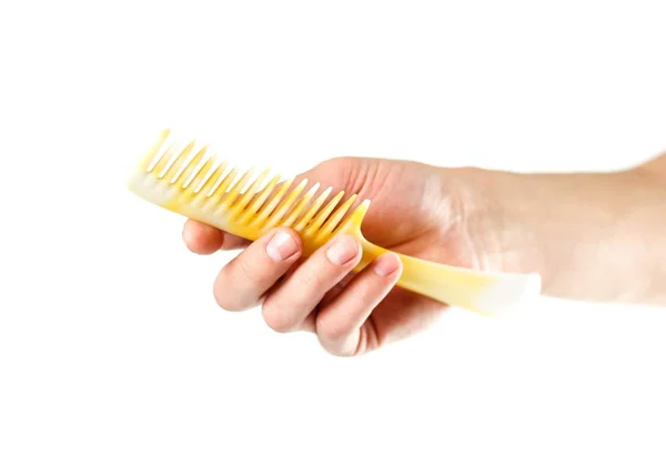 Ręcznie trzymając żółtą plastikową szczoteczkę do włosów. Z bliska. Izolowane w — Zdjęcie stockowe