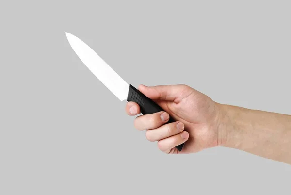 The hand holding the white ceramical knife. Close up. Isolated o — Stock Photo, Image