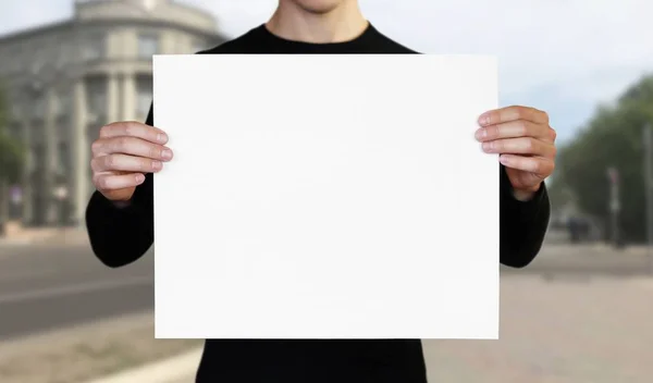 Ein Mann hält ein weißes Blatt Papier. In der Hand ein Büchlein. schließen u — Stockfoto